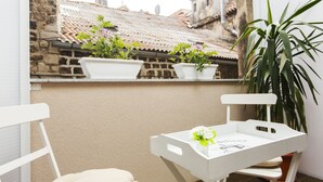 A balcony with white chairs, a small table with a tray, and potted plants. - Prior Suites Split (Split)