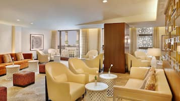 A hotel lobby with a sofa set, armchairs, a coffee table, and a decorative wall.