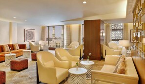 A hotel lobby with a sofa set, armchairs, a coffee table, and a decorative wall.