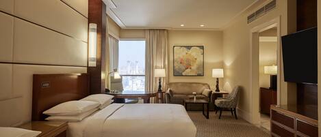 A hotel room with two beds, a desk, a chair, a TV, and a large window with a city view.