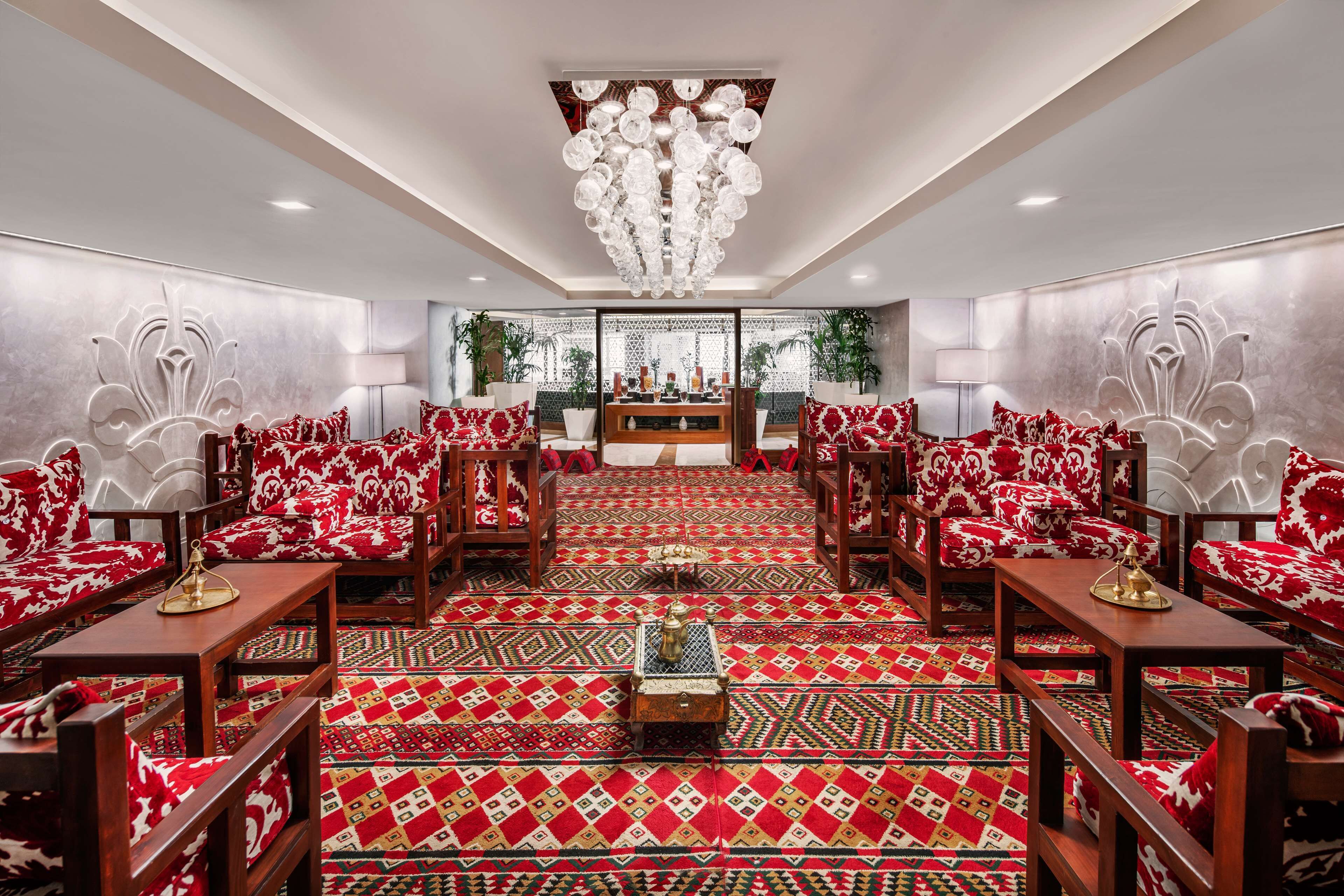 Una habitación amplia con alfombra estampada, muebles de madera y un candelabro.