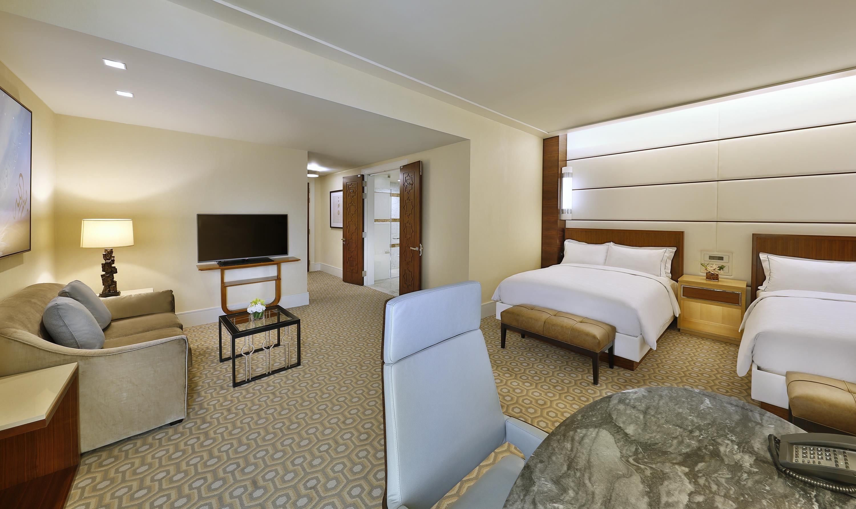 A hotel room with a bed, a sofa, a TV, a desk, and a phone.