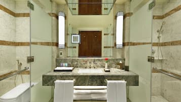 Un baño moderno con cabina de ducha de vidrio, lavamanos de mármol y puerta de madera.
