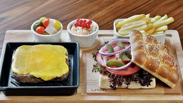 Una bandeja con un sándwich de queso a la plancha, una hamburguesa, papas fritas y dos ensaladas.