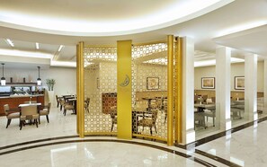 A hotel lobby with a central decorative partition, a reception area, and seating arrangements. - Conrad Jabal Omar Makkah (Makkah)