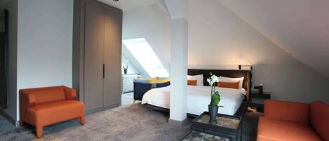 A modern hotel room with a loft bed, a sofa, a coffee table, and a view of the city.