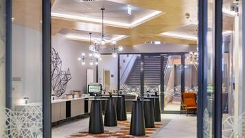 A modern interior with a central bar area, geometric wall art, and a staircase leading to an upper level.