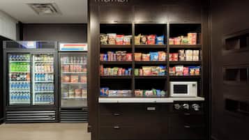 A vending machine area with snacks and drinks, a microwave, and a trash bin.