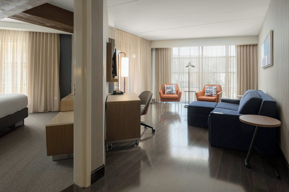 Ein Hotelzimmer mit einem Bett, einem Schreibtisch, zwei Sesseln, einem Sofa und einem kleinen runden Tisch.