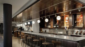 A modern bar area with a long counter, multiple stools, and overhead lighting. - Courtyard by Marriott Gatlinburg Downtown (Gatlinburg)