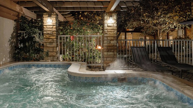 An indoor swimming pool with a stone wall, lounge chairs, and a fire feature. - Courtyard by Marriott Gatlinburg Downtown (Gatlinburg)
