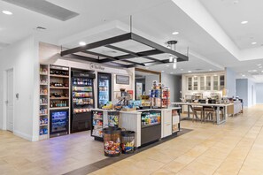Un espai comercial modern amb secció de begudes refrigerades i congelades, una cafeteria i una zona de cuina.