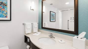 A bathroom with a large mirror, a sink, a toilet, and a framed floral artwork on the wall.
