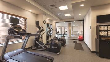A gym with treadmills, elliptical machines, and a red exercise ball.