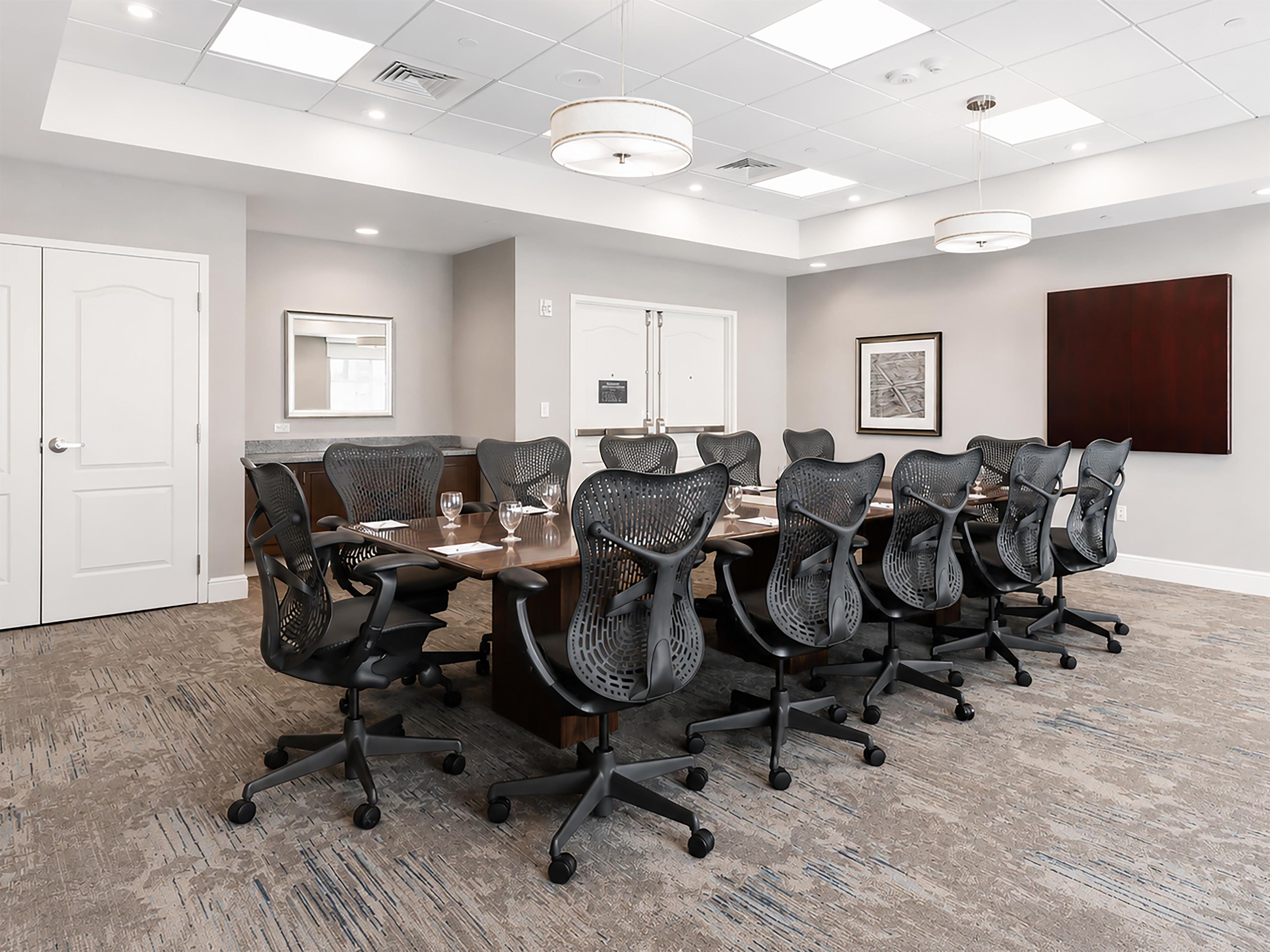 A conference room with a long table, multiple chairs, and a large window.