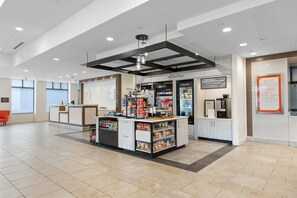 A modern interior with a reception desk, a coffee shop area, and a dining section.