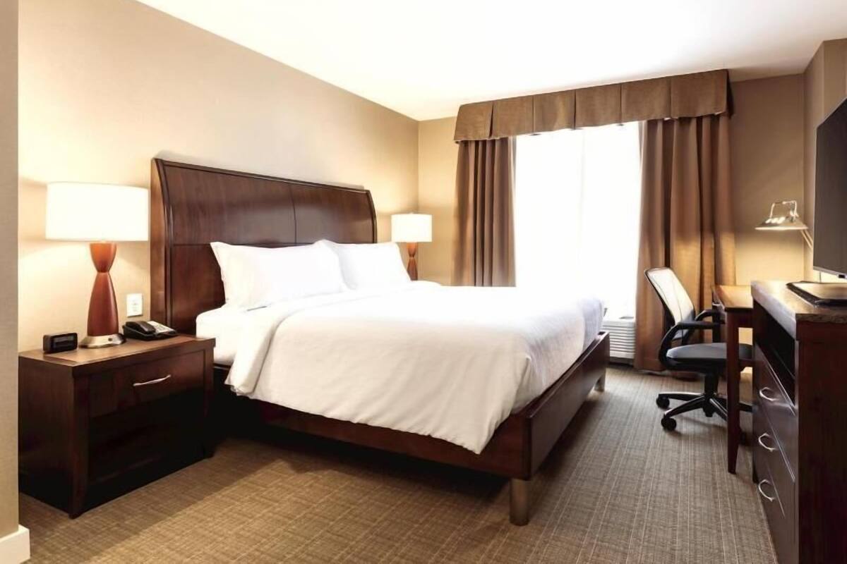 A hotel room with a large bed, bedside tables, a desk, and a chair.