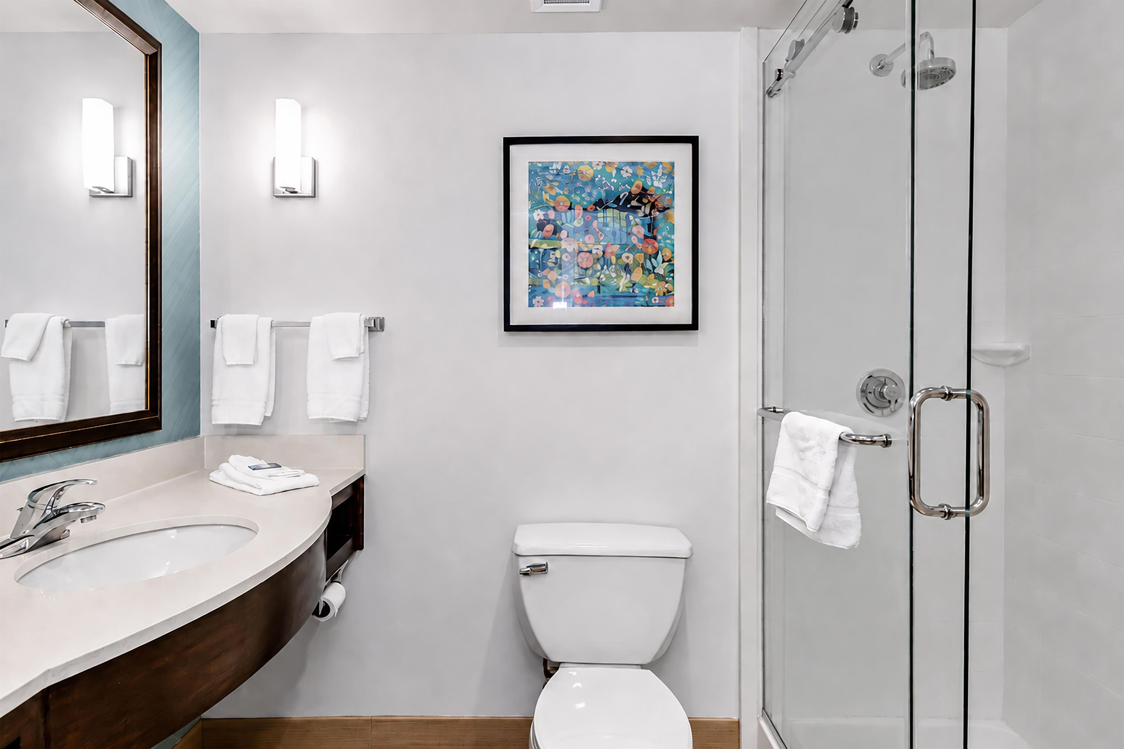 Een moderne badkamer met een grote spiegel, een wastafel, toilet en douche.