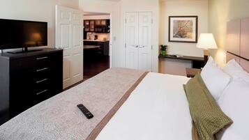 Une chambre d’hôtel avec un lit, une télévision, un bureau et, au fond, une kitchenette.