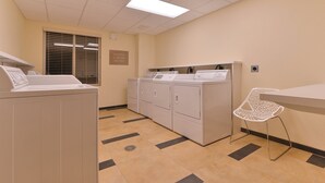 A laundry room with multiple washers and dryers, a chair, and a sign indicating free use of washers and dryers. - Candlewood Suites Casper by IHG (Casper)