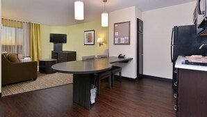 A compact hotel room with a dining area, a sofa, a TV, and a kitchen counter. - Candlewood Suites Casper by IHG (Casper)