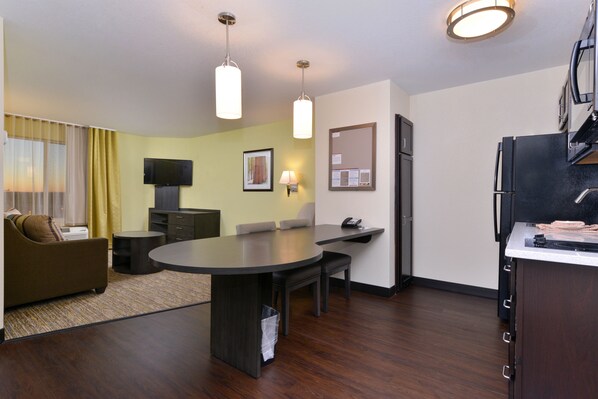 A compact hotel room with a dining area, a sofa, a TV, and a kitchen counter. - Candlewood Suites Casper by IHG (Casper)