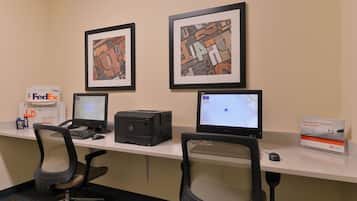 Un espacio de trabajo con dos escritorios, cada uno con monitor, teclado y ratón. Hay obras de arte enmarcadas en la pared sobre los escritorios.