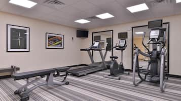 A fitness center with treadmills, elliptical machines, and a bench.
