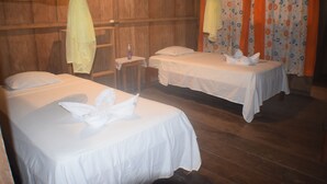 Ein Zimmer mit zwei Betten, Holzwänden und einem Vorhang mit Blumenmuster.