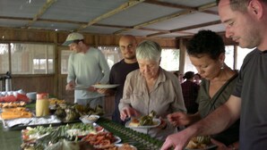 Eine Gruppe von Personen bedient sich an einem Buffet mit verschiedenen Speisen.