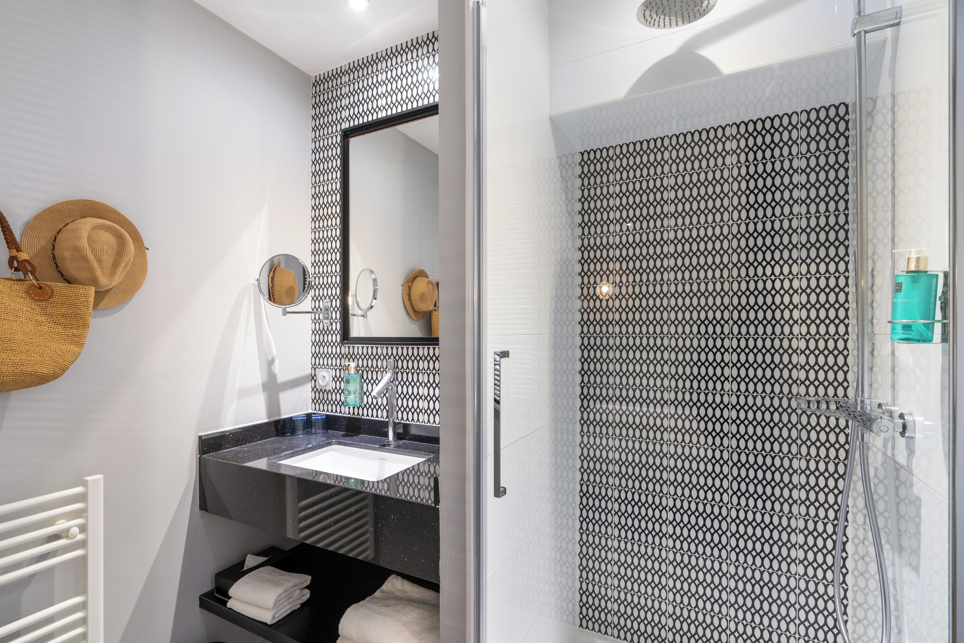 A bathroom with a sink, mirror, and shower.
