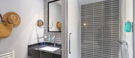 A bathroom with a sink, mirror, and shower.