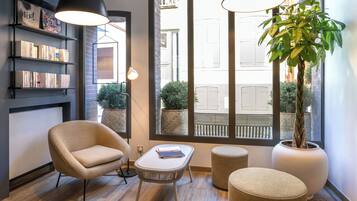 Un intérieur moderne avec une grande fenêtre, une bibliothèque, un fauteuil, une petite table et une plante en pot.