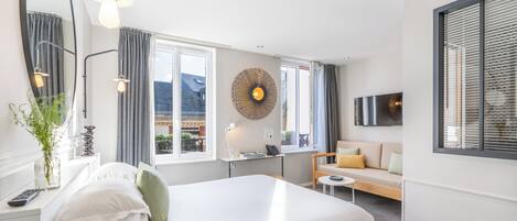 Una habitación de hotel moderna con una cama grande, un escritorio, un sofá y un televisor.