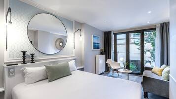 Habitación de hotel moderna con una cama grande, un espejo redondo, un escritorio y vistas al exterior.