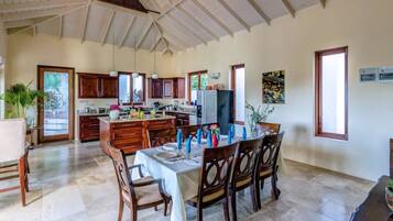 A spacious kitchen with wooden cabinets, a dining area with a table set for six, and a large window providing natural light.
