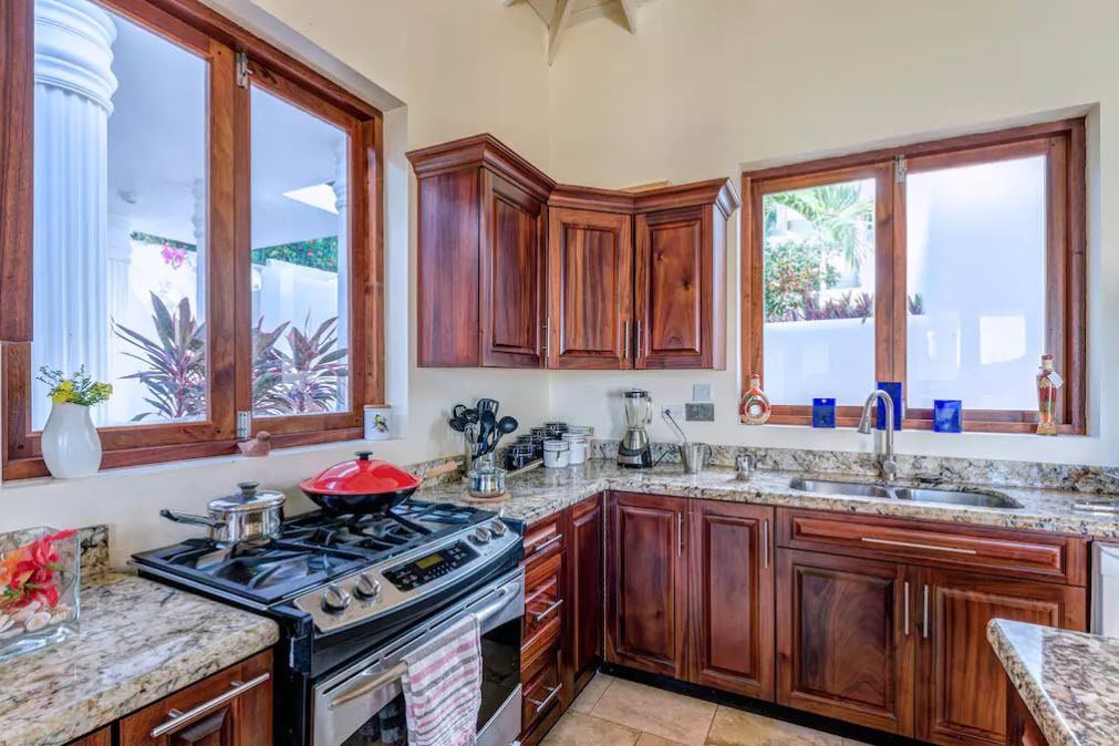A kitchen with wooden cabinets, a granite countertop, a stove, and a sink.