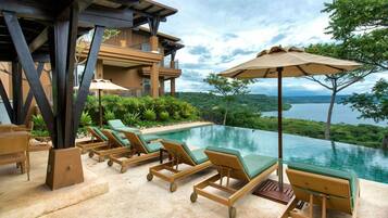 Relax by the pool surrounded by lush greenery and a serene natural landscape.