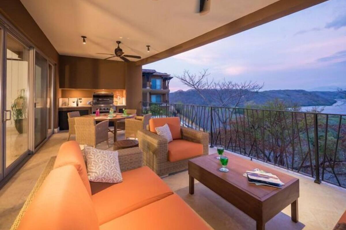 A balcony with a sofa, chairs, and a table.