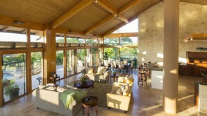 Uma sala de estar espaçosa com teto alto, janelas grandes e vista para o exterior.