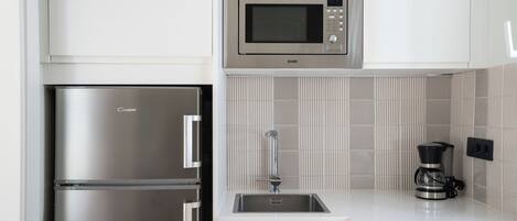 A modern kitchen with a stainless steel refrigerator, a microwave, and a coffee maker.