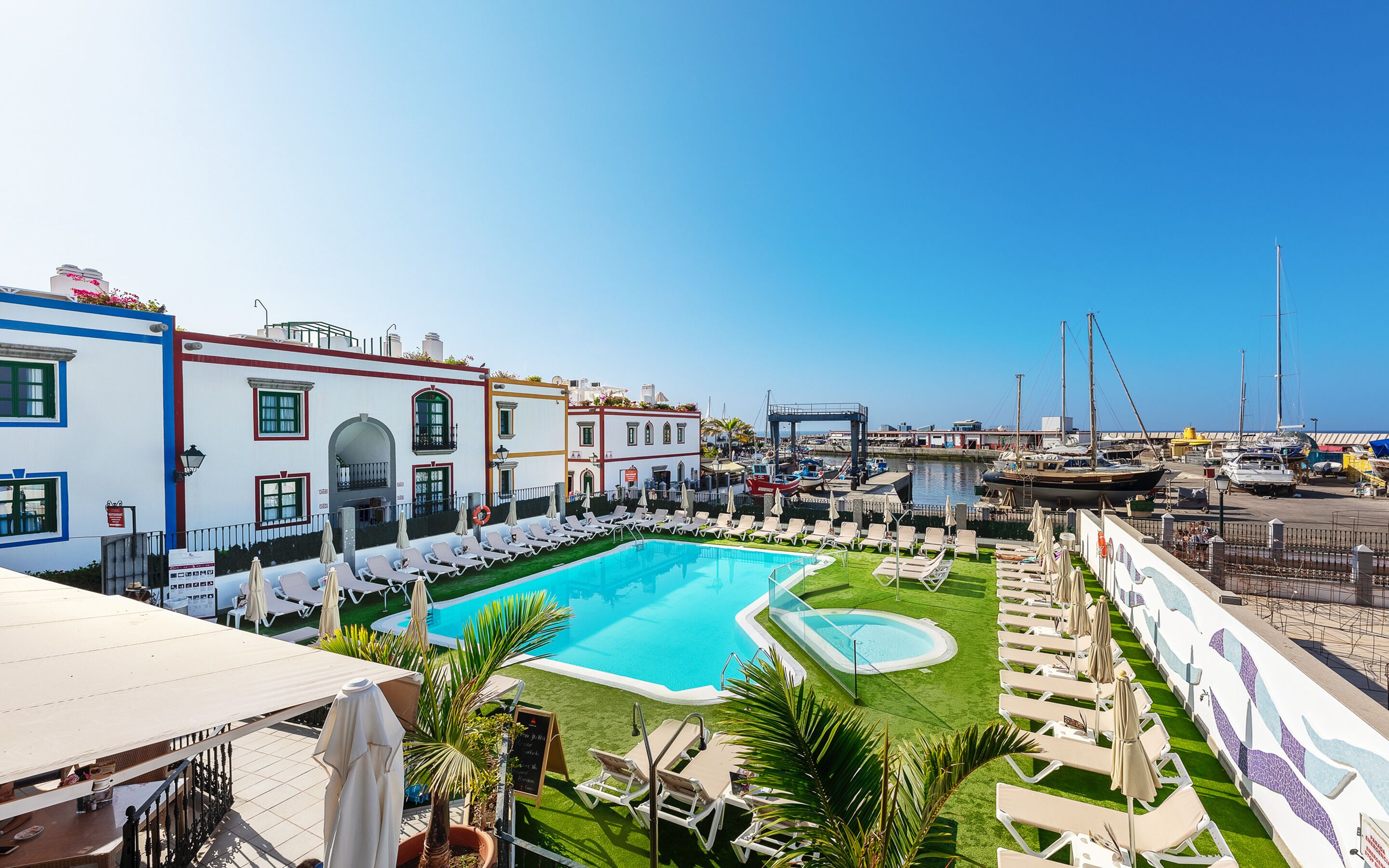 Ein Poolbereich mit Liegestühlen und Blick auf den Hafen.