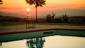 A swimming pool with a table and chairs, surrounded by a landscaped garden and a sunset view. - Tenuta Torre Rossa Farm & Apartments (Impruneta)