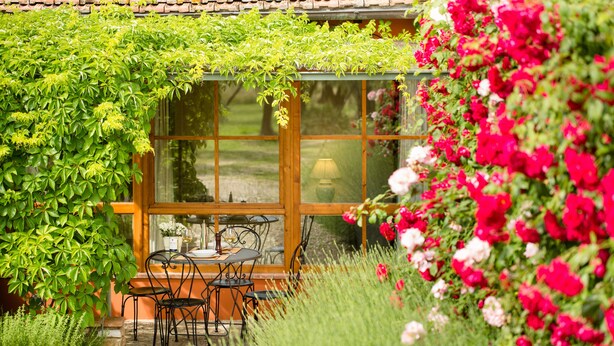 A cozy outdoor seating area with a table and chairs, surrounded by lush greenery and vibrant flowers. - Tenuta Torre Rossa Farm & Apartments (Impruneta)