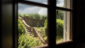 A view through a window of a stone wall and a stone staircase leading to a higher level. - Tenuta Torre Rossa Farm & Apartments (Impruneta)
