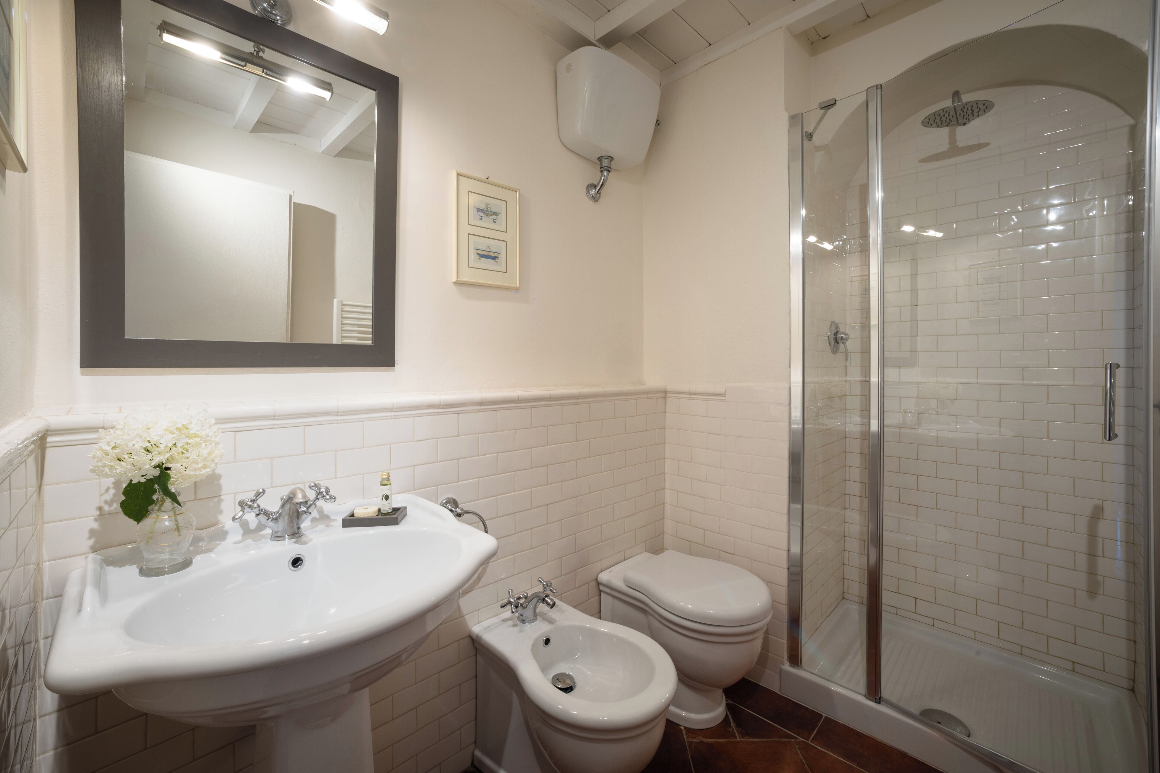 Un baño con lavamanos, bidé, inodoro y ducha con mampara de vidrio.