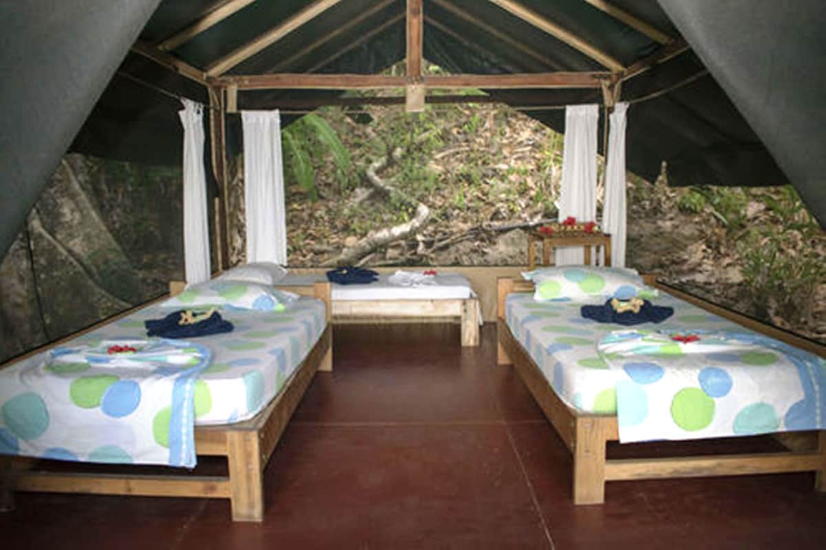 A tent with two beds, each with a polka dot bedspread, and a bench in the center.