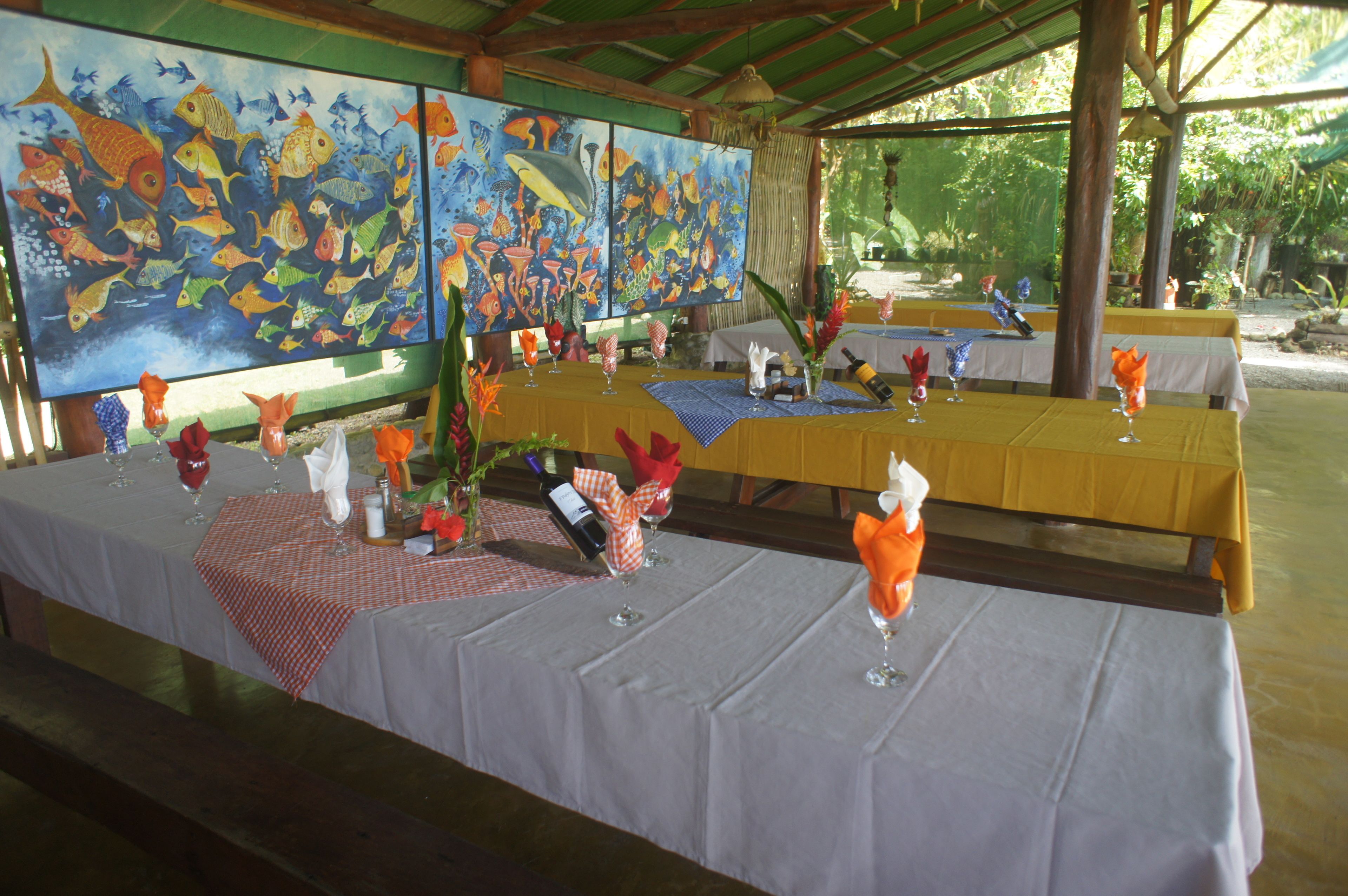 A dining area with tables set for a meal, featuring a large mural of fish on the wall.