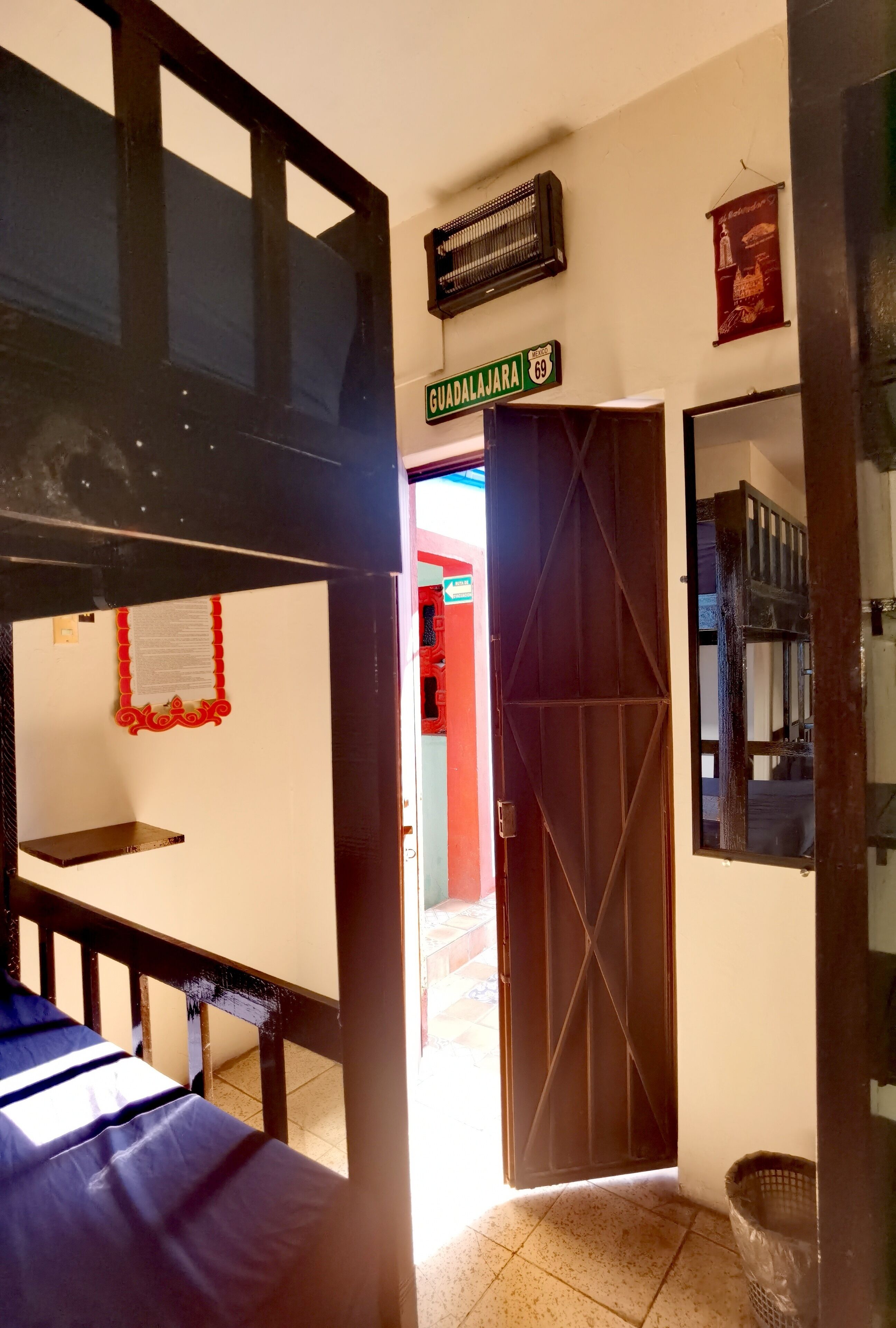 A room with a bed, a door, a wall-mounted sign, and a tiled floor.