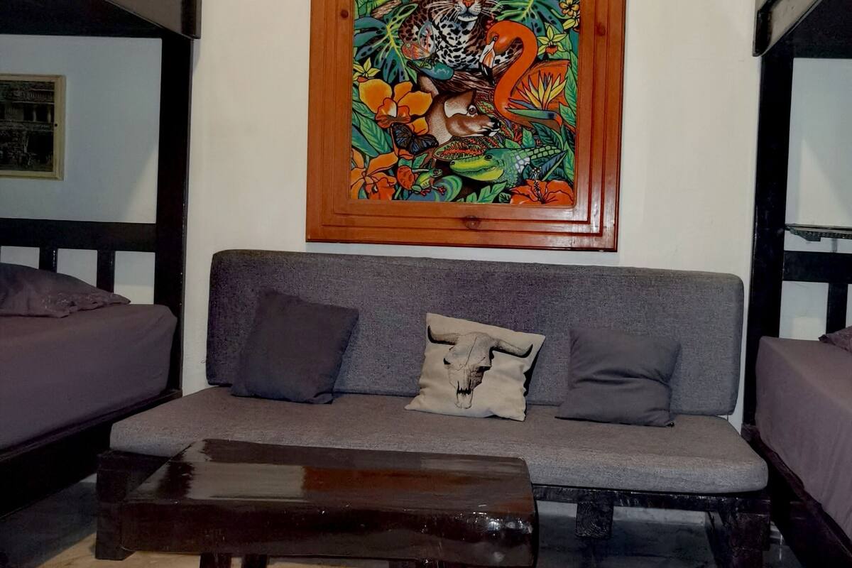 Una stanza con un divano, un tavolino di legno e un letto a castello con una foto incorniciata del Guatemala appesa al muro.